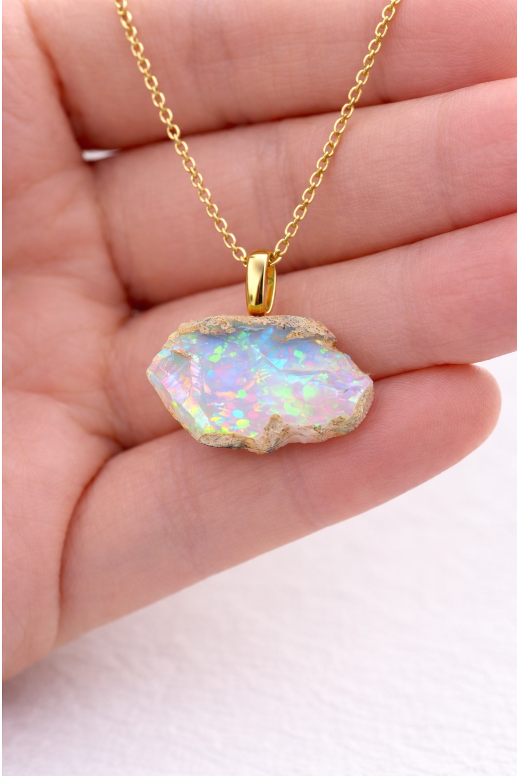 Opal pendant necklace on a hand with a light background