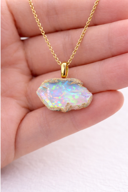 Opal pendant necklace on a hand with a light background